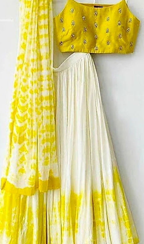 A yellow and white embroidered suit with a dupatta, hanging after cleaning